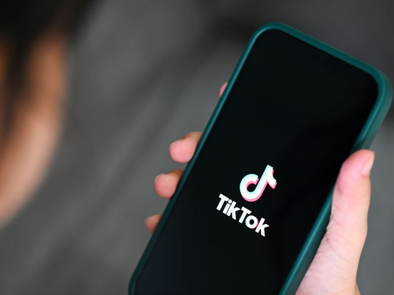 Closeup of hand holding smart phone with the logo of the video app TikTok on the screen.