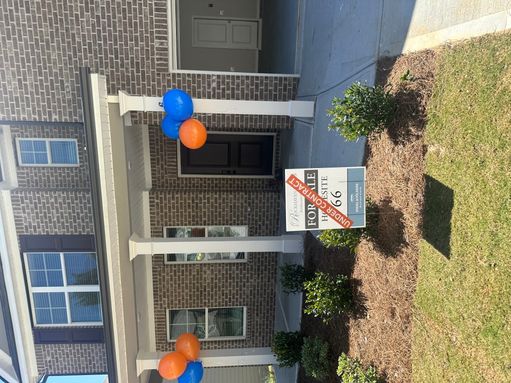A home with orange and blue balloons and an 'under contract' sign in the front yard.